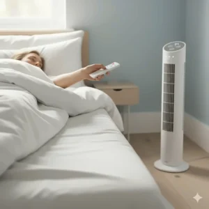 A person lying under a white duvet using a remote control to adjust a quiet tower fan from across the room.