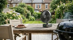 A cordless rechargeable fan used outdoors on a patio table during a garden BBQ, showing portability without mains power.