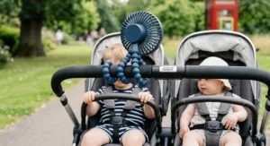 An octopus-style flexible tripod fan wrapped securely around the handle of a double pushchair.