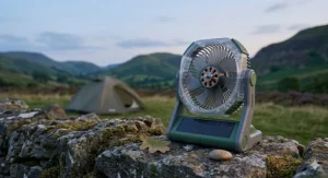 A detailed 4K close-up photograph illustrating the engineering internals of the portable solar powered camping fan, standing on a weathered stone wall at dusk to convey quiet performance.