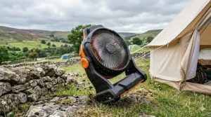 A robust, durable rechargeable fan for camping placed on a stone wall in damp, misty British moorland conditions.