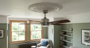 Close-up detail of a modern black ceiling fan with an integrated LED light, installed within a traditional white plaster ceiling rose in a UK lounge.