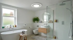 A detailed, photorealistic 4K overview of a modern British bathroom bathed in soft natural daylight, featuring the integrated circular ceiling-mounted extractor fan unit. This view highlights the clean environment and efficient ventilation after mould remediation.