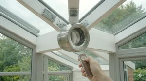 A compact, powerful USB-powered desk fan sitting on a side table next to a cup of tea in a small lean-to conservatory.