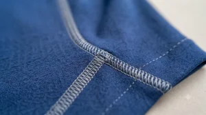 A stack of folded, colourful sports cooling shirts on a wooden shelf.