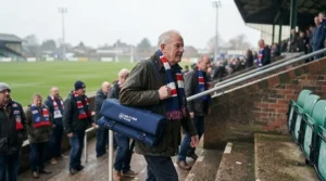 Spectator easily carrying a lightweight portable stadium cushion over their shoulder walking up stadium steps to a rugby match.