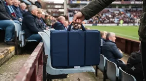Compact folding stadium seat cushion with a convenient carry handle for football fixtures.