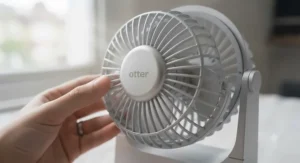 Hands easily removing the front safety grille of a USB-C desk fan for quick dusting and cleaning