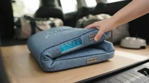 A folded portable blue cooling pad placed inside a car boot, demonstrating a practical summer travel accessory for dogs on the move.